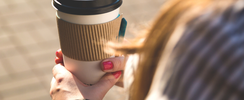 A woman holding a takeaway cup of coffee.