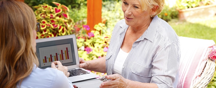 Female financial planner showing a senior woman charts on a laptop.