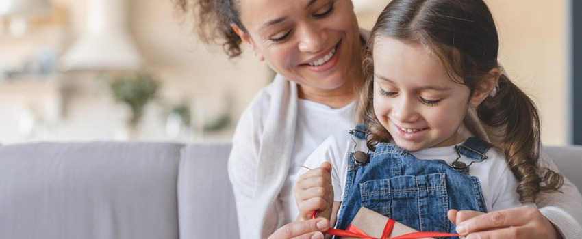 A mother and daughter unwrapping a gift.
