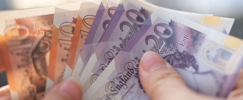 A person holding UK bank notes.