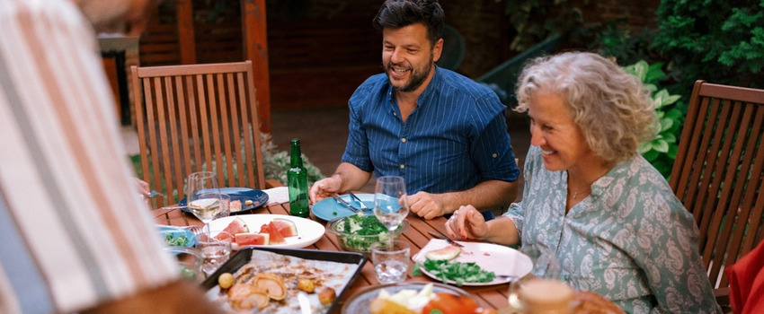 A multigenerational family eating together outdoors.