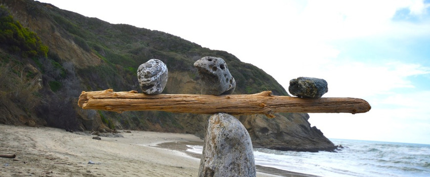 Rocks balancing on log on top of another rock