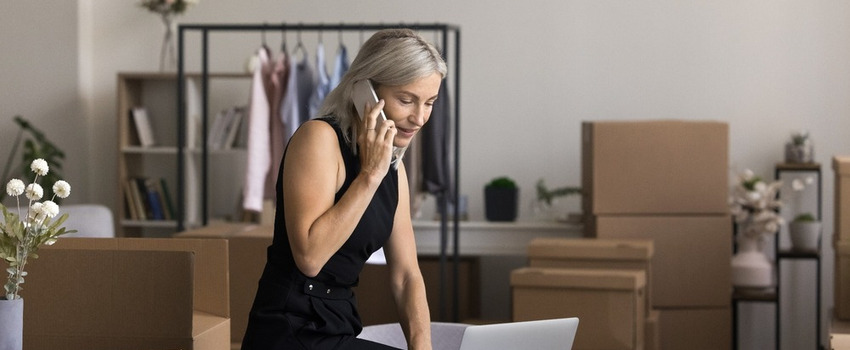 Female boss taking notes on a laptop as she discusses with someone on the phone