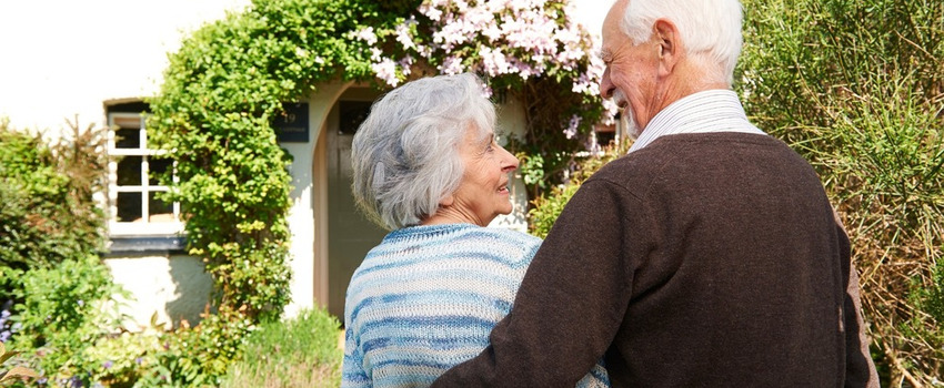 Rear view of senior couple outside pretty cottage